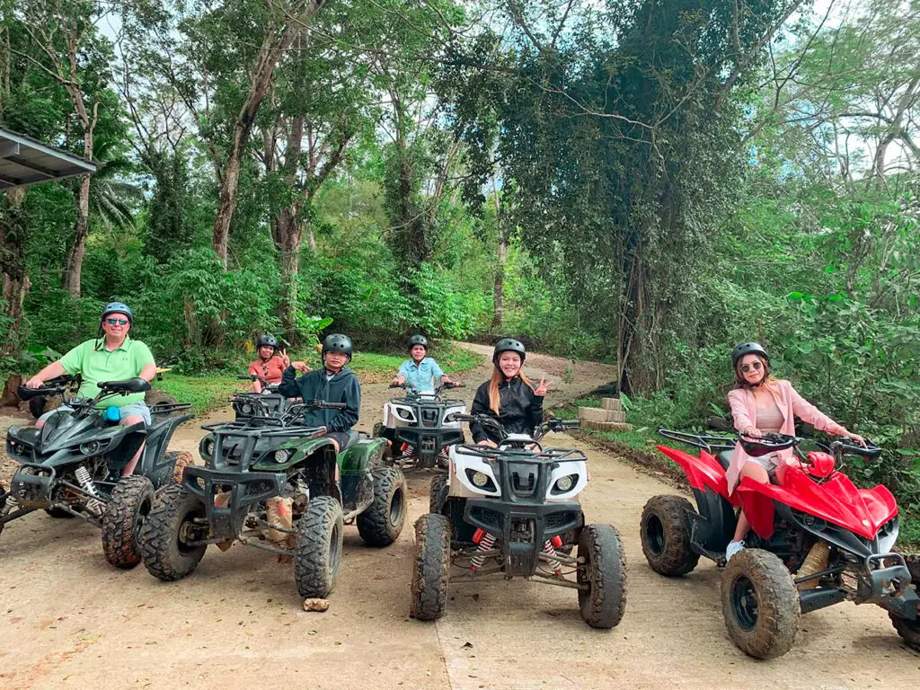 Luxe Drive Digital Marketing America's Top Marketing Agency A group of seven people wearing helmets are sitting on parked ATVs on a dirt path in a forested area, enjoying a Luxe Drive experience that could be highlighted in any adventurous digital marketing campaign. Luxe Drive Digital Marketing We Drive Your Growth