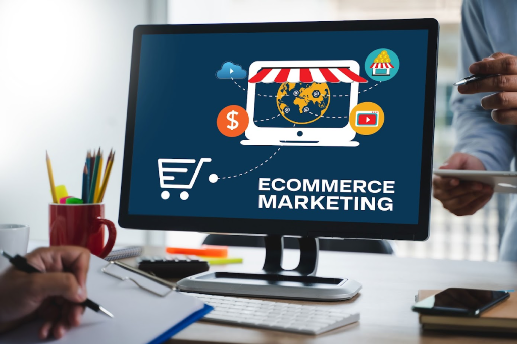 Luxe Drive Digital Marketing America's Top Marketing Agency A computer screen displaying "Ecommerce Marketing" with various digital marketing icons, while people review documents and use a smartphone nearby. Luxe Drive Digital Marketing We Drive Your Growth