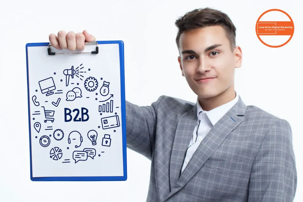 Luxe Drive Digital Marketing America's Top Marketing Agency Man in a suit holding a clipboard with business icons and "B2B" written on it. An orange circular logo is in the background. Luxe Drive Digital Marketing We Drive Your Growth