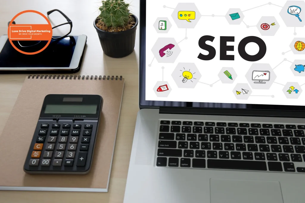 Luxe Drive Digital Marketing America's Top Marketing Agency Workspace with a laptop displaying "SEO," calculator, notebook, tablet, and a small cactus on a desk. Luxe Drive Digital Marketing We Drive Your Growth