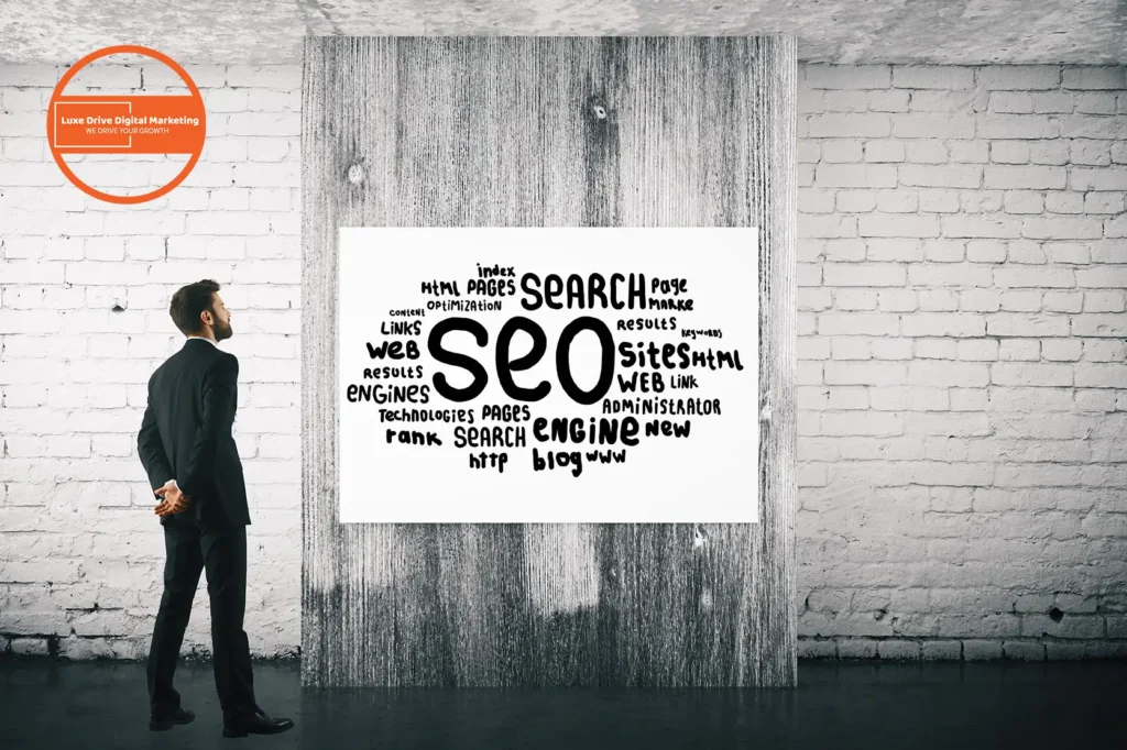 Luxe Drive Digital Marketing America's Top Marketing Agency A man in a suit looks at a word cloud poster about SEO on a textured wall. Luxe Drive Digital Marketing We Drive Your Growth