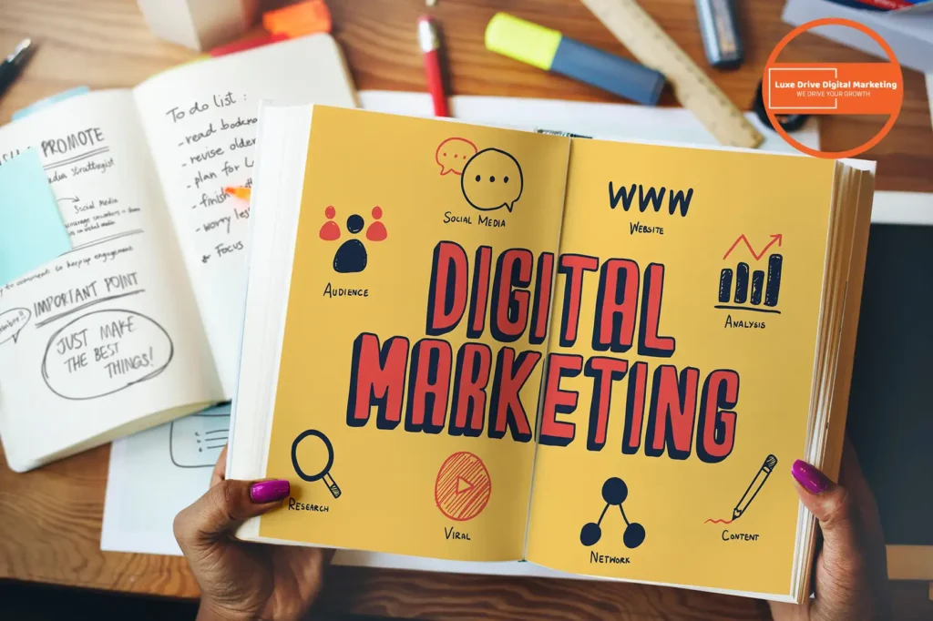 Luxe Drive Digital Marketing America's Top Marketing Agency Person holding a book titled "Digital Marketing" surrounded by notebooks, highlighting social media, website, audience, viral, research, analysis, and content concepts. Luxe Drive Digital Marketing We Drive Your Growth